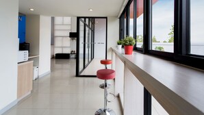 A modern hotel corridor with a bar area featuring a red stool and potted plants. - Hop Inn Roi Et (Roi Et)