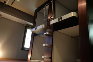 Un baño moderno y compacto con ducha integrada, inodoro y ventana con persianas.