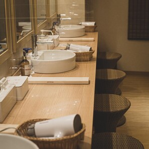 A modern bathroom with multiple sinks, a mirror, and wicker baskets.