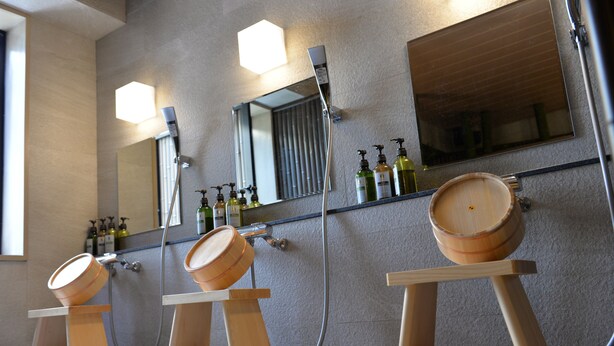 Une salle de bain avec des tonneaux en bois, un grand miroir et de nombreuses bouteilles de produits de toilette.