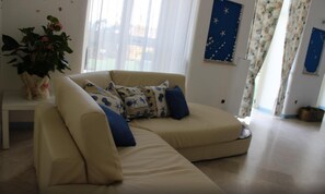 Un salon avec un canapé beige, une plante en pot et un mur orné d’un motif étoilé.