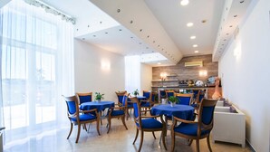 A dining area with tables and chairs, a kitchen in the background, and large windows. - Hotel Stella Maris Terme & Beauty (Casamicciola Terme)