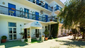 A hotel with a white facade, blue balconies, and a covered entrance area with potted plants. - Hotel Stella Maris Terme & Beauty (Casamicciola Terme)