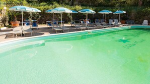 A swimming pool with lounge chairs and umbrellas, surrounded by a stone wall and greenery. - Hotel Stella Maris Terme & Beauty (Casamicciola Terme)