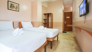 A hotel room with two single beds, a wooden wardrobe, a television mounted on the wall, and a painting on the wall.