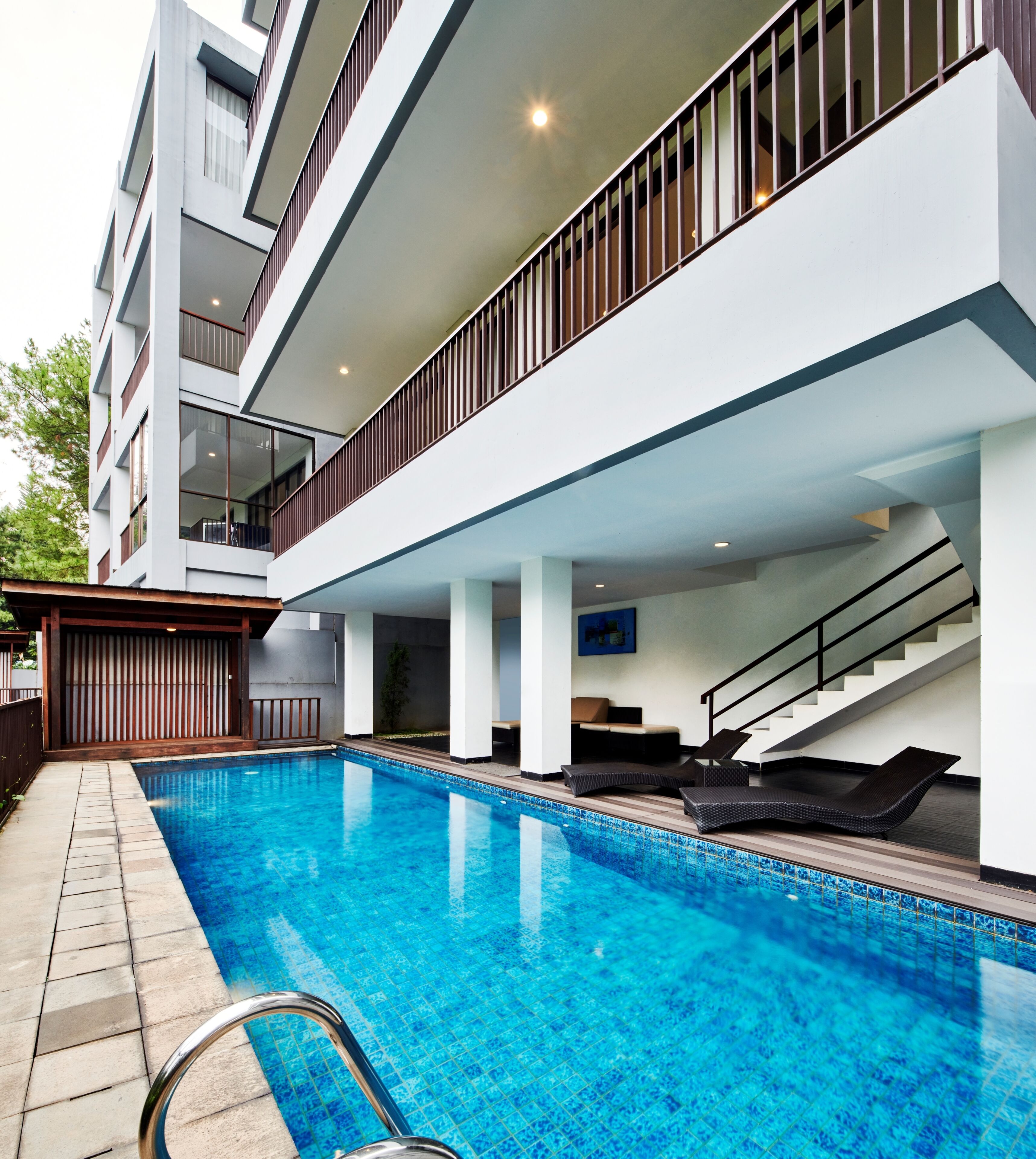A modern building with a swimming pool, outdoor seating, and a staircase.