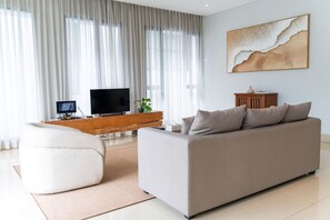 Ein modernes Wohnzimmer mit einer Couch, einem Fernseher, einem Holzschrank und einem großen abstrakten Gemälde an der Wand.