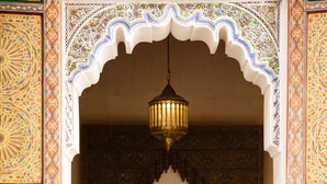 A room with a bed, a hanging light fixture, and ornate wall decorations.