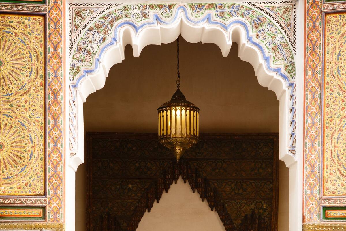 A room with a bed, a hanging light fixture, and ornate wall decorations.