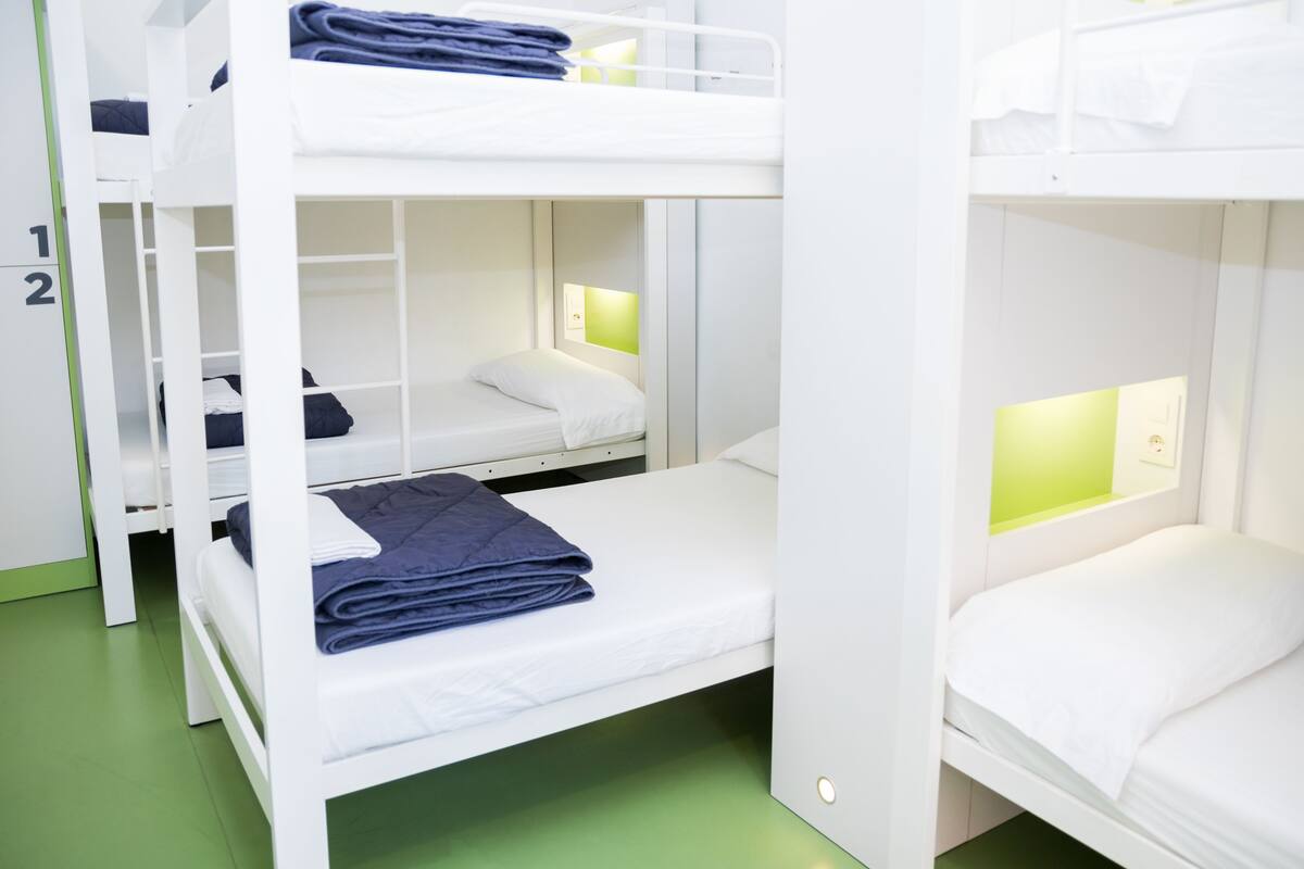 Habitación con literas, dos camas, cada una con almohada y manta doblada.