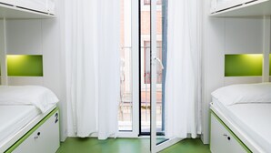 Una habitación con dos literas, una puerta corrediza de vidrio y piso verde.