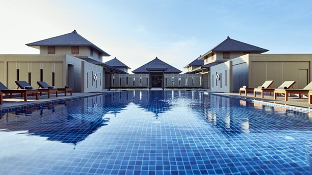 A swimming pool with lounge chairs and a covered walkway. - Serenity Hotel Spa & Onsen (Kabin Buri)