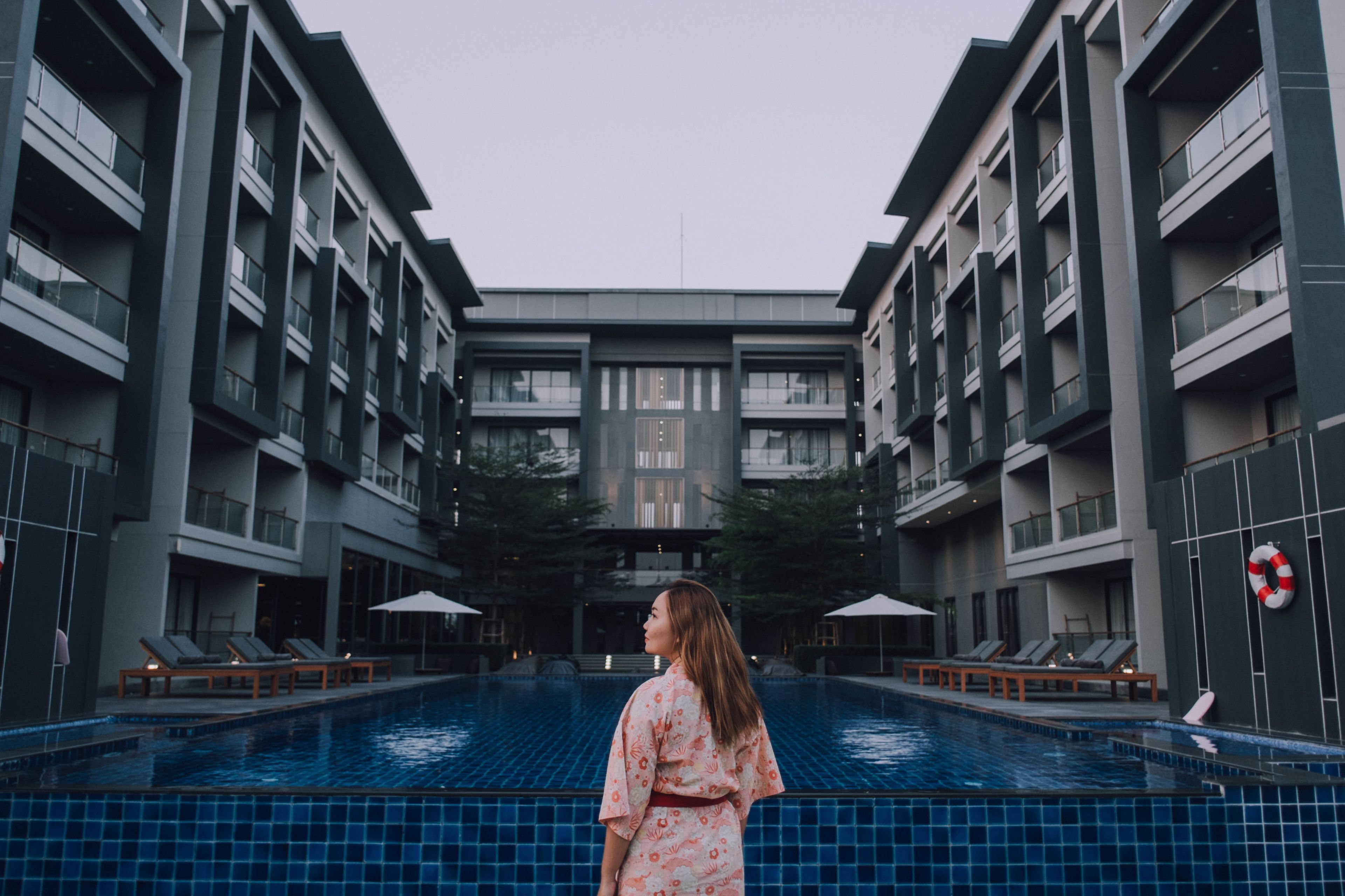 A modern building with a central courtyard pool, lounge chairs, and umbrellas.