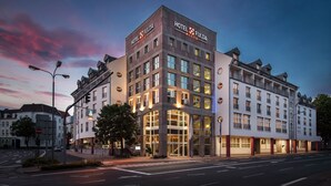A modern hotel with a prominent entrance, multiple floors, and a well-lit facade.