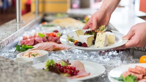A buffet with various food items including meats, cheeses, and fruits.