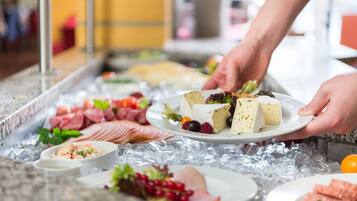 A buffet with various food items including meats, cheeses, and fruits.
