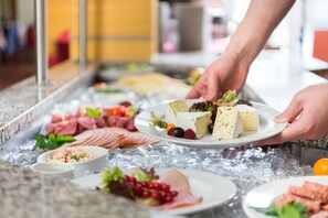 A buffet with various food items including meats, cheeses, and fruits.