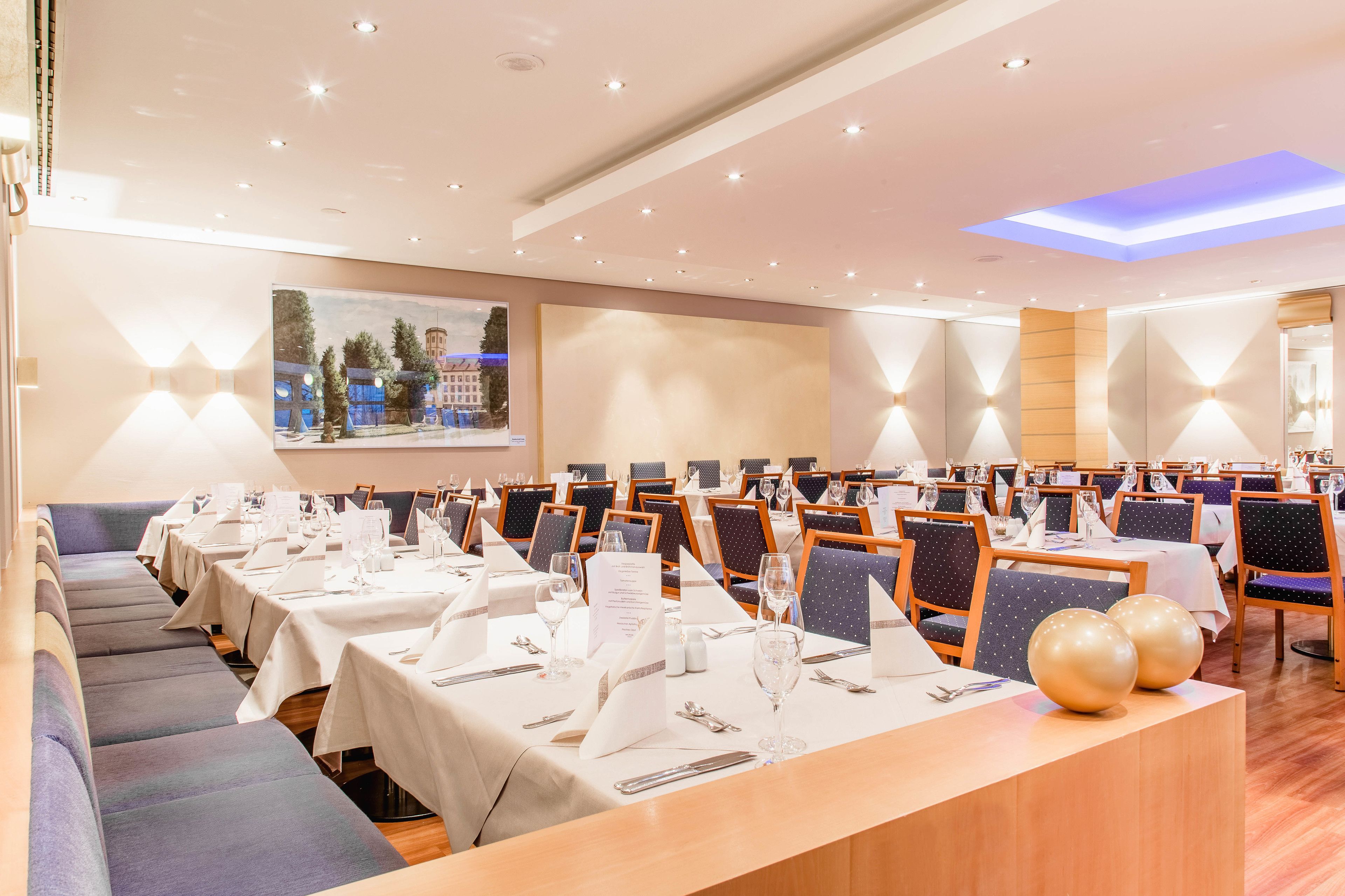 A conference room with multiple tables and chairs, equipped with name cards, water glasses, and menus.
