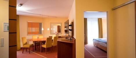 Una habitación de hotel con cama, escritorio y zona de comedor con sillas.