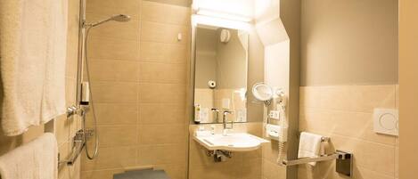 Een kleine badkamer met douche, wastafel en toilet.