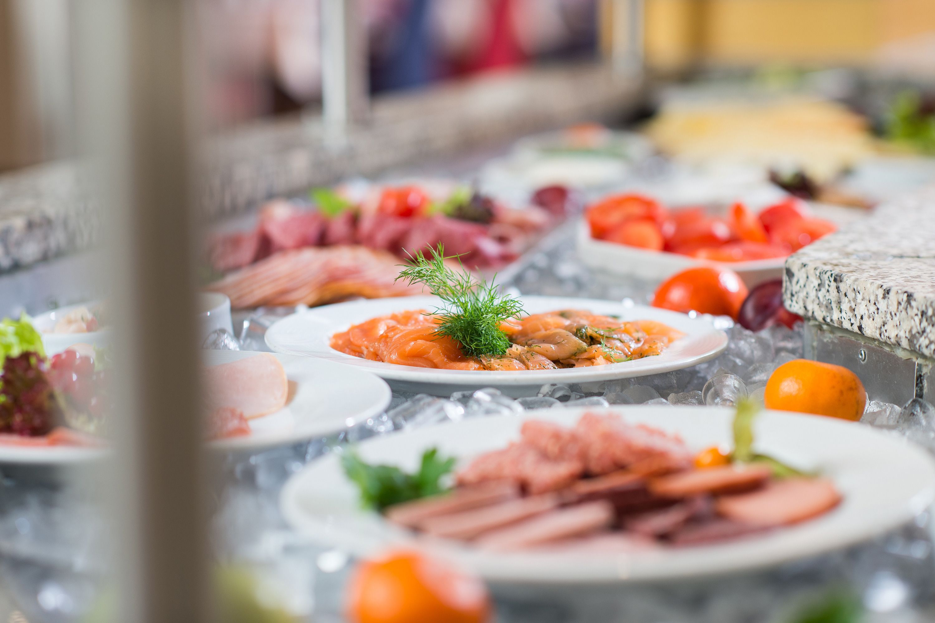 A variety of food items displayed on a table with ice, including meats, cheeses, and vegetables.