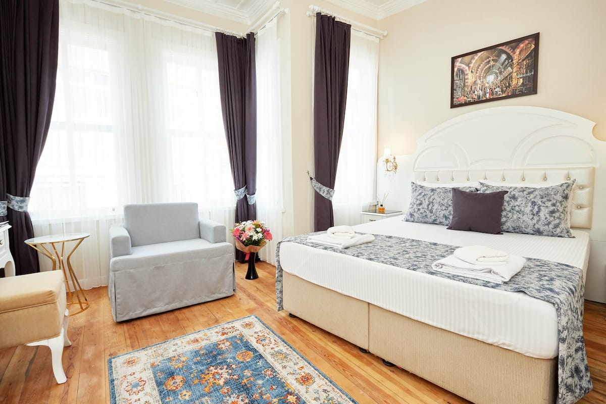 Et hotelværelse med seng, sofa, et lille bord og en dekorativ måtte.