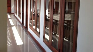 A long, polished hallway with wooden ceiling and large windows. - Chalouvanh Hotel (Pakse)