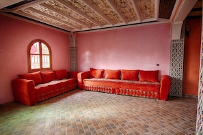 A room with a red sofa, patterned tiles, and a decorative ceiling.