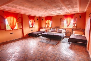 A bedroom with a large bed, two smaller beds, and a bench.