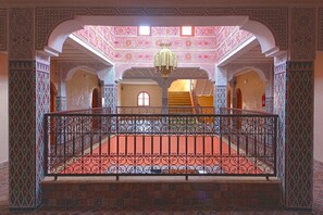 Een versierd interieur met een centrale open ruimte, decoratieve bogen en een patroonvloer.