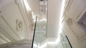 Una imponente escalera con decoraciones ornamentales en las paredes y barandilla de cristal.