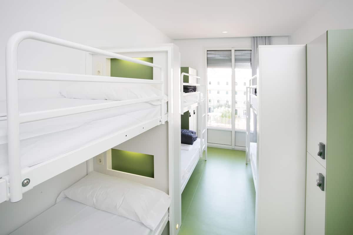 Habitación con literas, suelo verde, ventana y puerta.