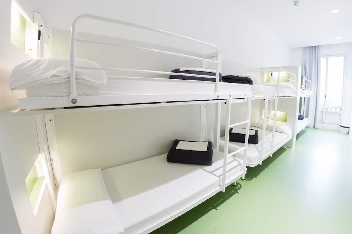 Varios catres en una habitación con suelo verde y paredes blancas.