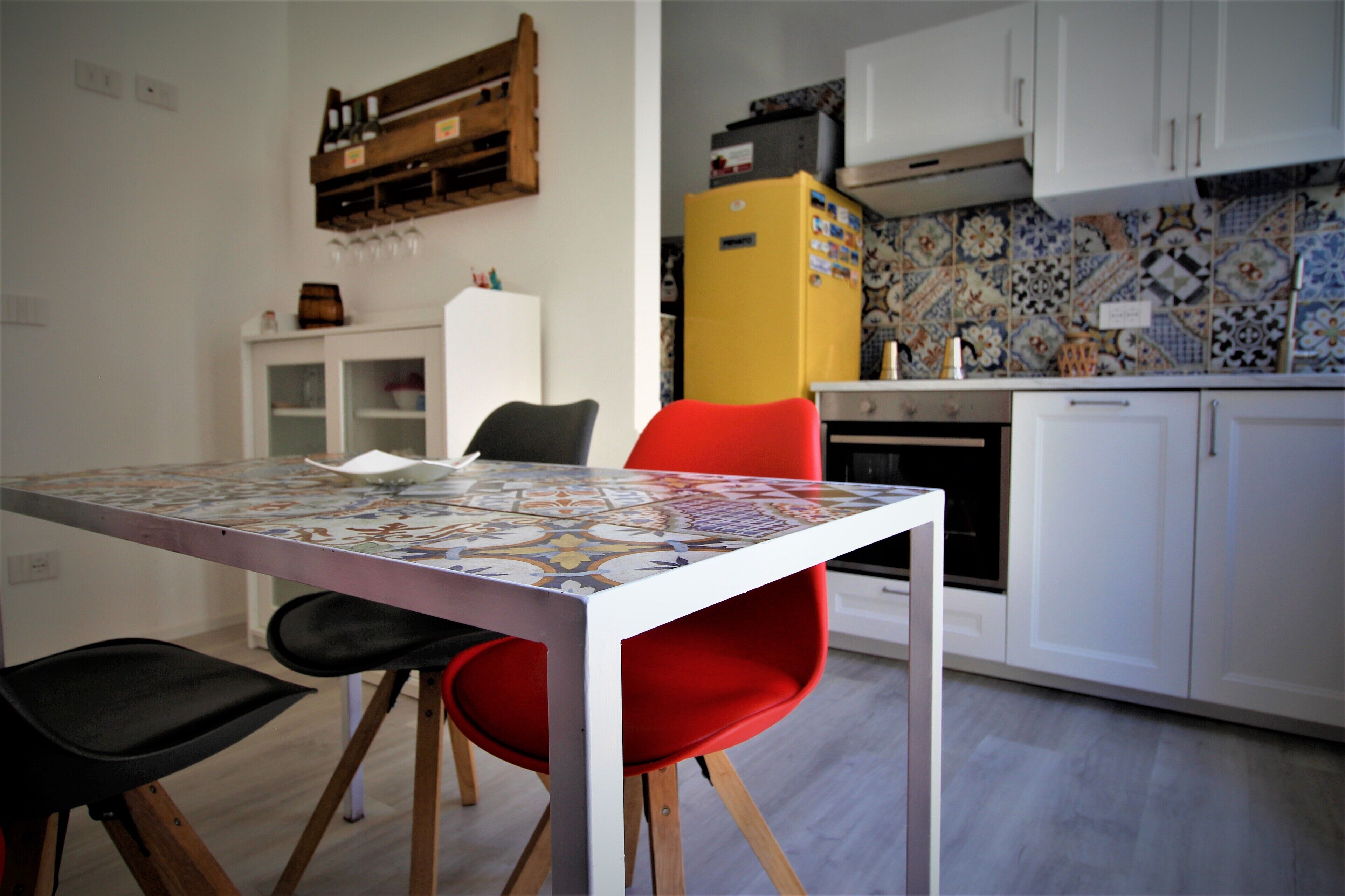 Una cocina con salpicadero de azulejos, un refrigerador blanco y una mesa de comedor con sillas.