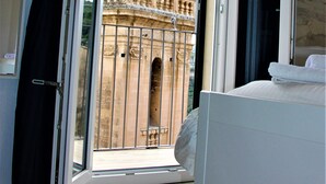 Una habitación con un ventanal grande, una cama y vistas a un edificio histórico con cúpula.