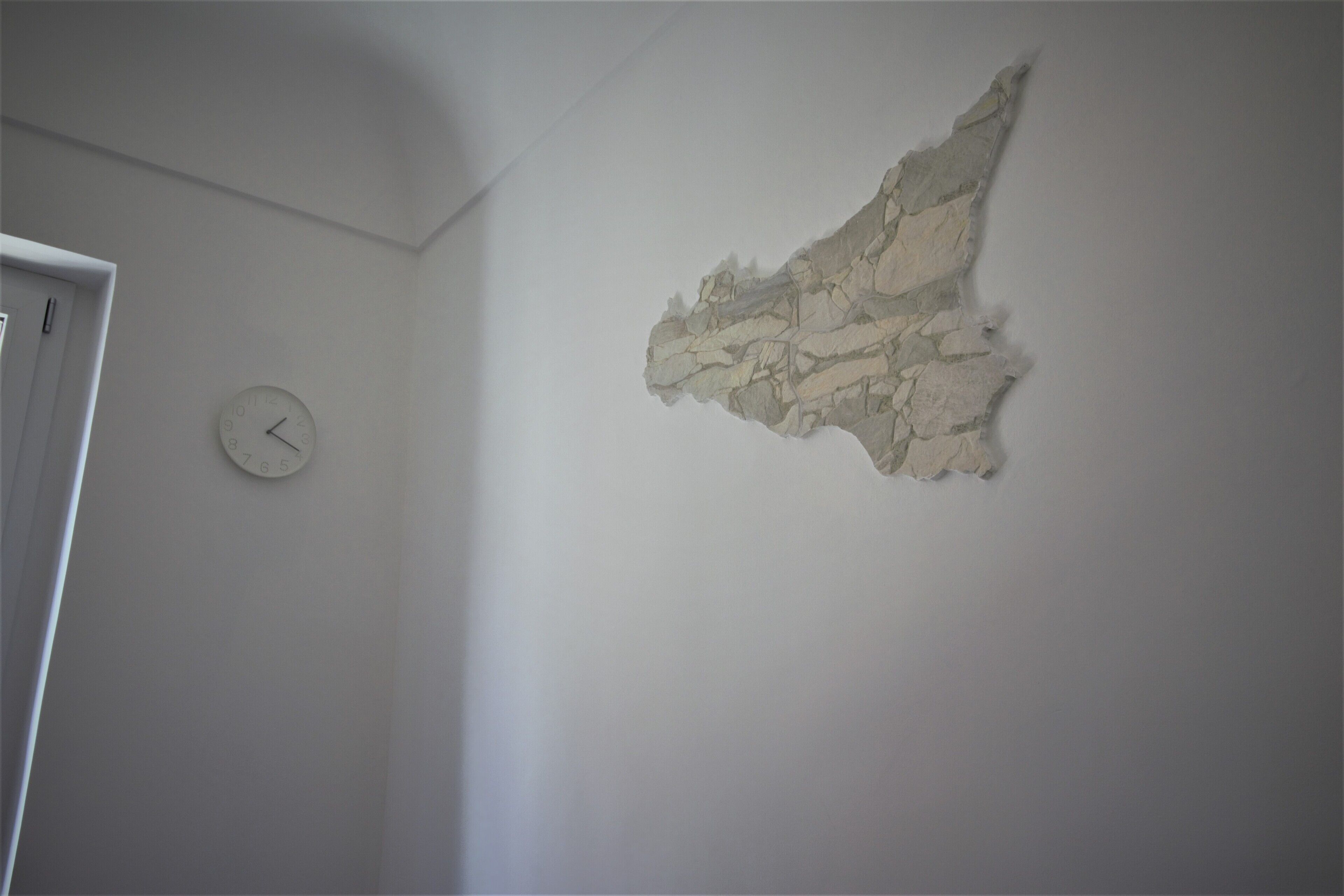 Une pièce avec une horloge au mur et un décor mural texturé.