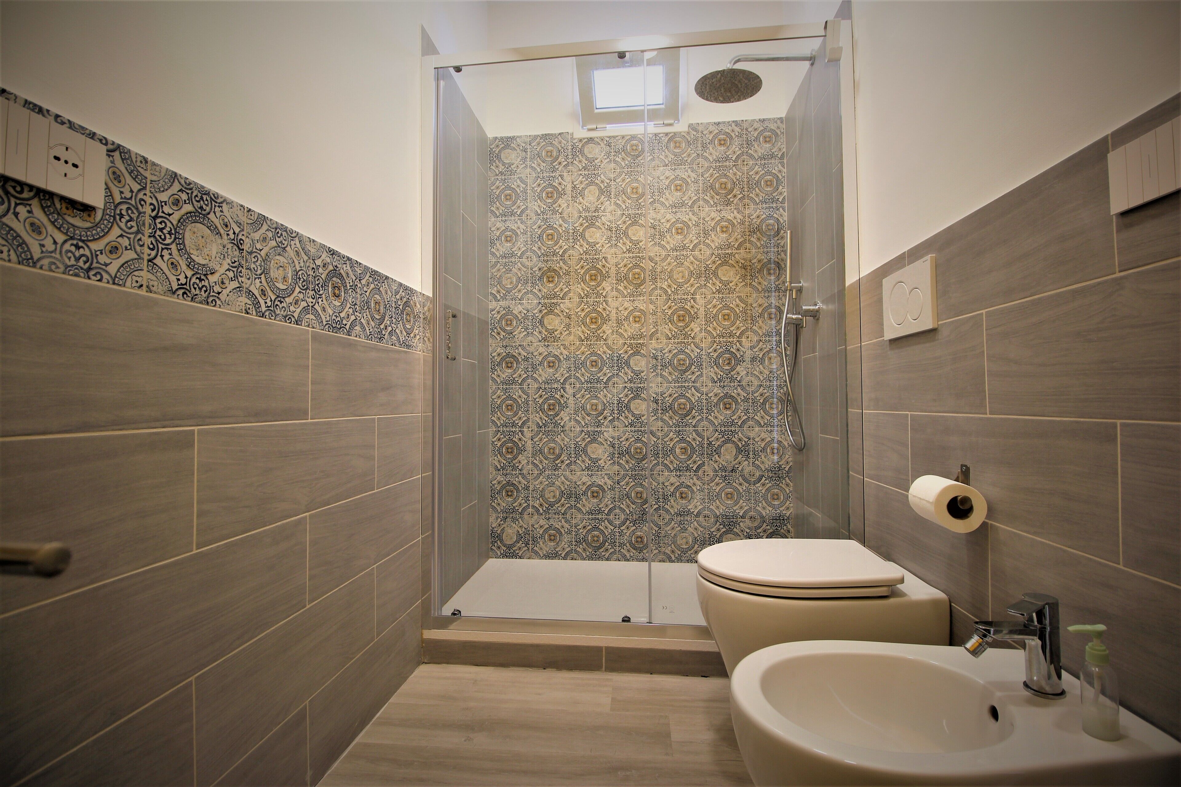 A bathroom with patterned tiles, a toilet, a sink, and a shower.