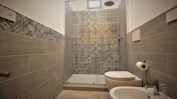 A bathroom with patterned tiles, a toilet, a sink, and a shower.