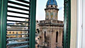 Vista a través de una ventana con rejas, mostrando un edificio histórico con cúpula y arquitectura detallada.