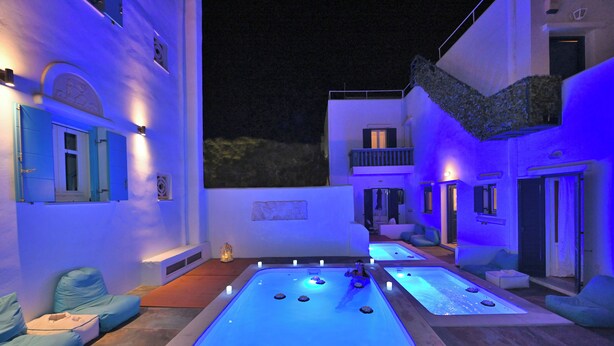 A modern outdoor pool area with seating and a stone wall. - Tinos Aqua Palazzo (Tinos)