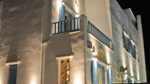 A multi-story building with white walls and blue accents, featuring balconies and decorative window frames. - Tinos Aqua Palazzo (Tinos)