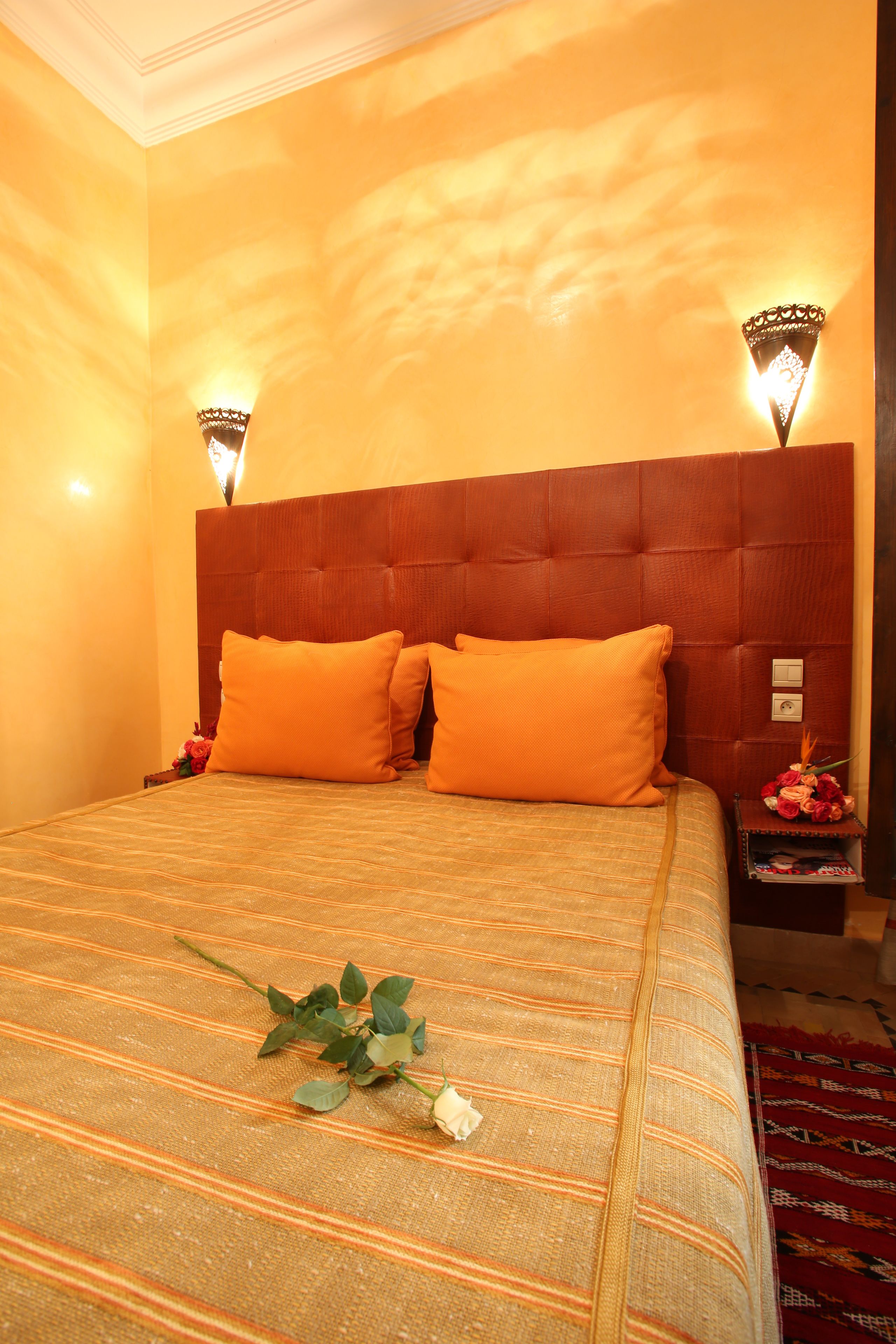 Habitación de hotel con una cama grande, dos apliques de pared y un cabecero rojo.