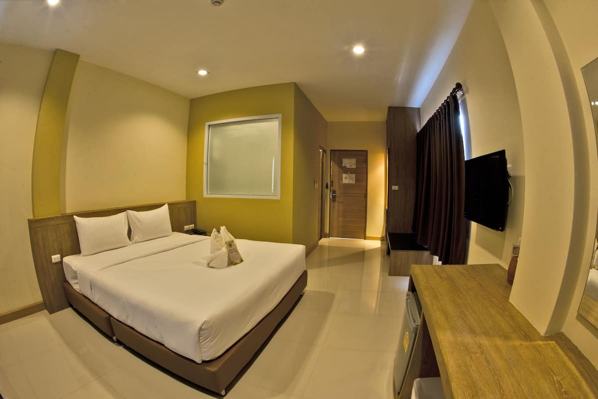 Una habitación de hotel con cama, escritorio, televisor y ventana.