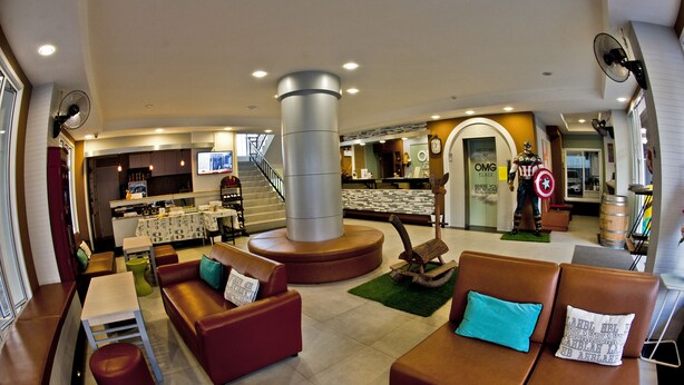 A spacious lobby with leather seating, a central pillar, and a reception area in the background. - OMG Hotel (Khon Kaen)