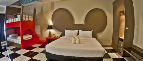A hotel room with a checkered floor, a large bed with white bedding, a red bunk bed, and a unique wall design.