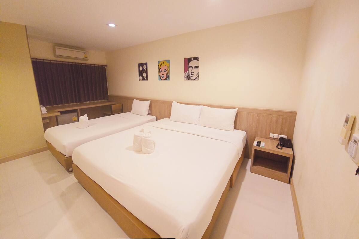 Una habitación de hotel con dos camas, cabecera de madera, mesita de noche y aire acondicionado instalado en la pared.