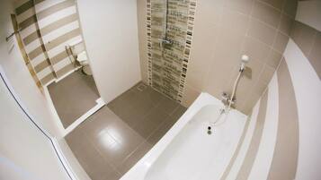 A bathroom with a bathtub, a toilet, and a shower area.