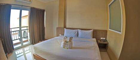 A hotel room with a large bed, a bedside table, a nightstand, and a window.