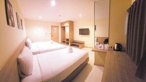 A hotel room with two beds, a wooden desk with a kettle, and a flat-screen TV on the wall. - OMG Hotel (Khon Kaen)