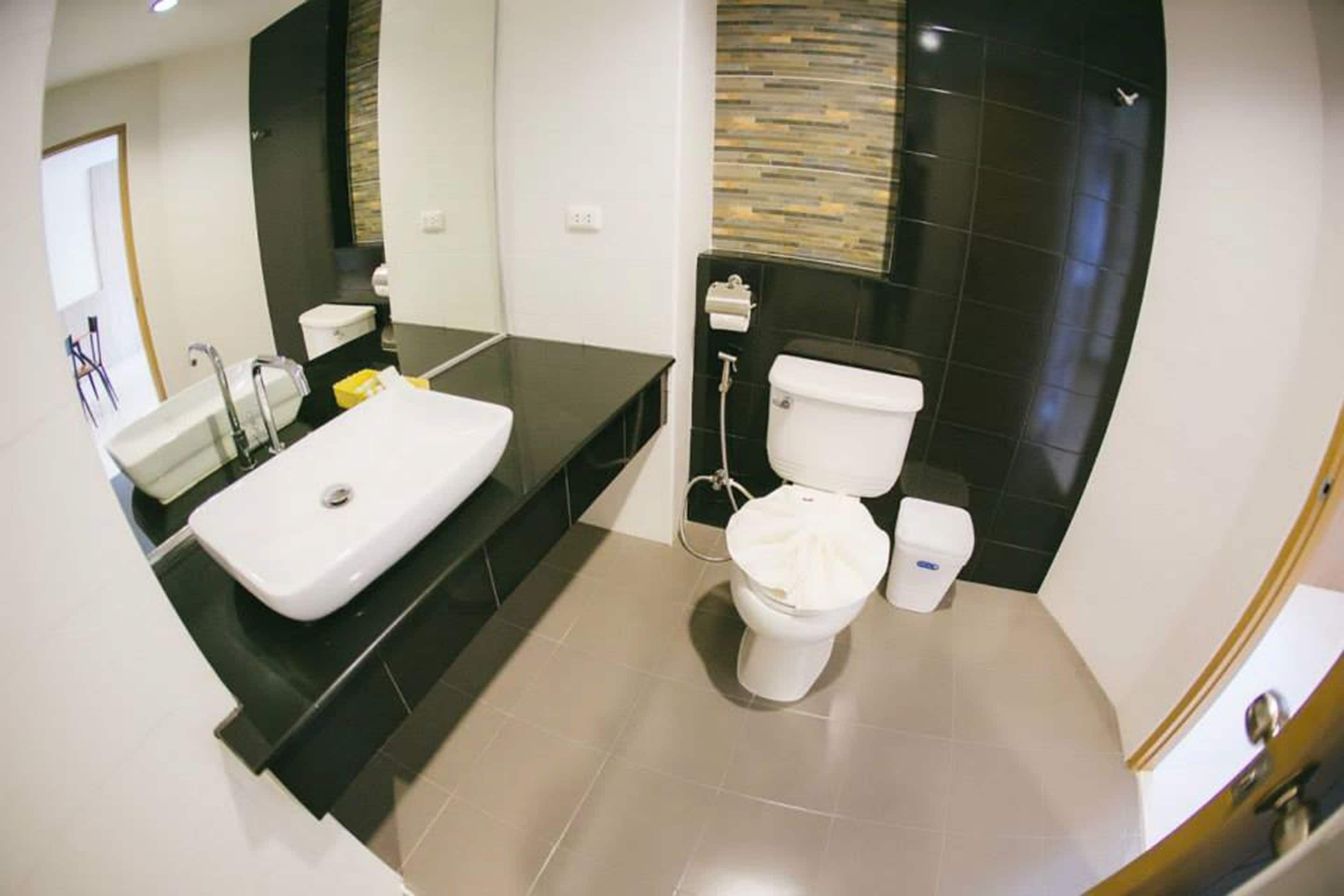 A modern bathroom with a white sink, black countertop, and a toilet with a bidet attachment.